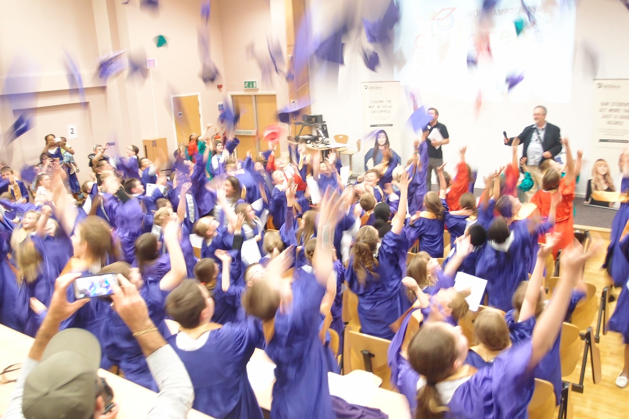 Child graduates throwing mortarboards in the air in celebration