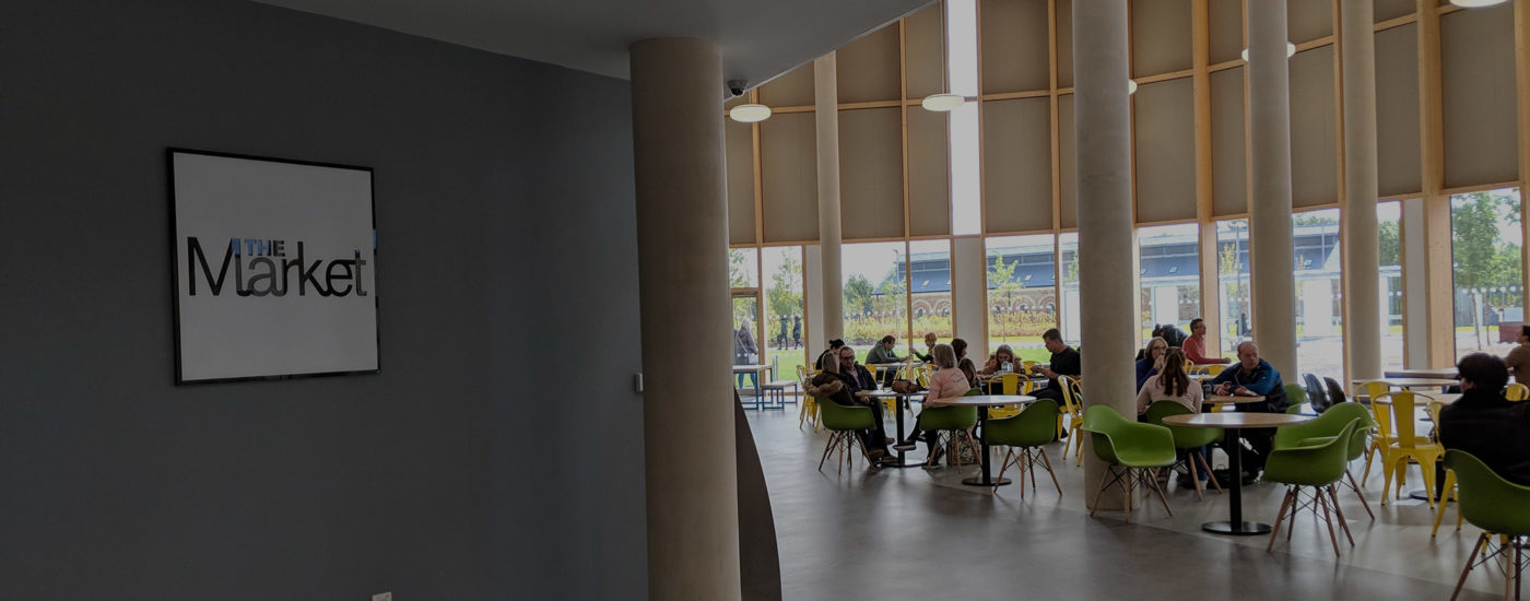 Students and visitors sitting at tables in The Market restaurant on campus.