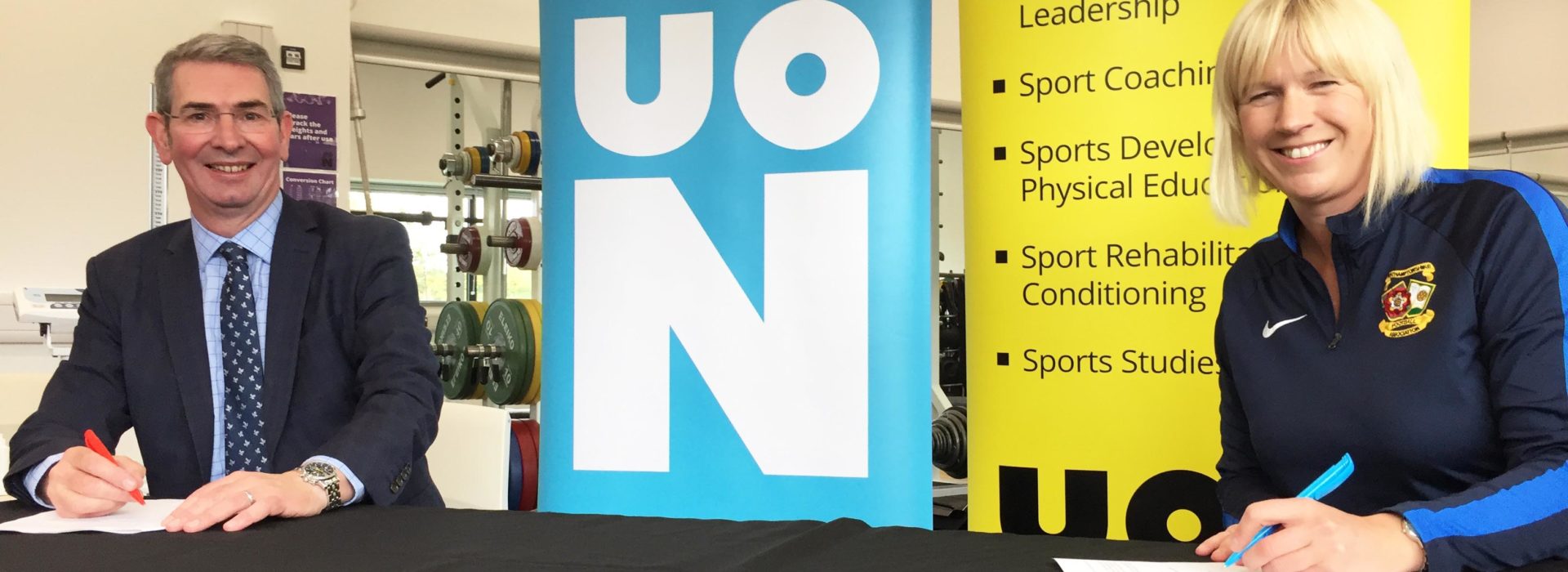 John Sinclair, Dean of the Faculty of Arts, Science and Technology at the University of Northampton, left, signs the MOU with Sarah Bentley, CEO of Northamptonshire Football Association.