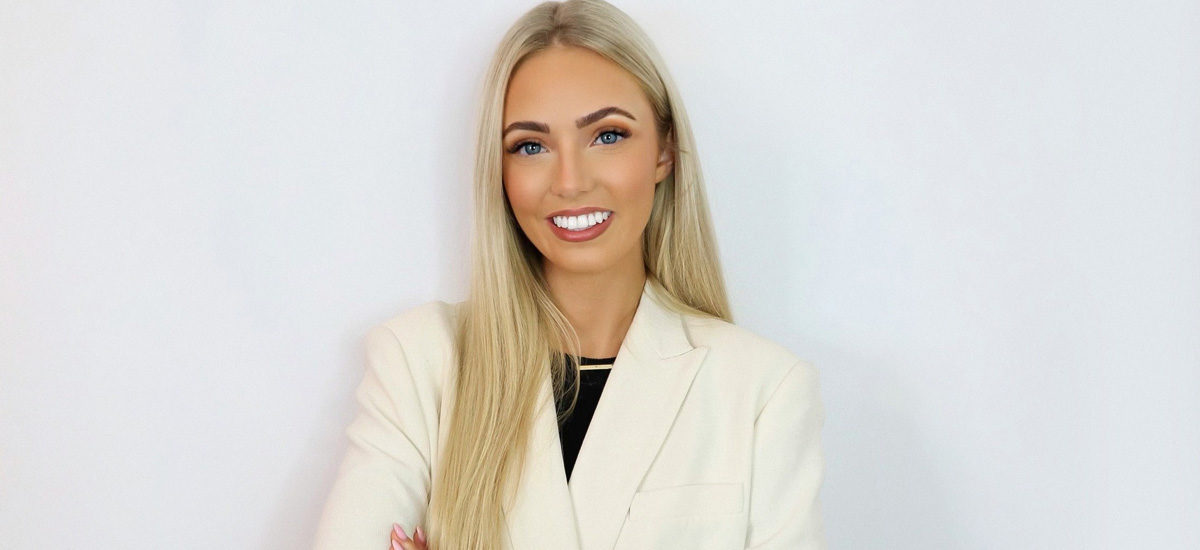 Photo of Jade Thomas, Psychology BSc (Hons) graduate of University of Northampton. Jade is wearing a white suit, looking towards the camera and smiling folding her arms.