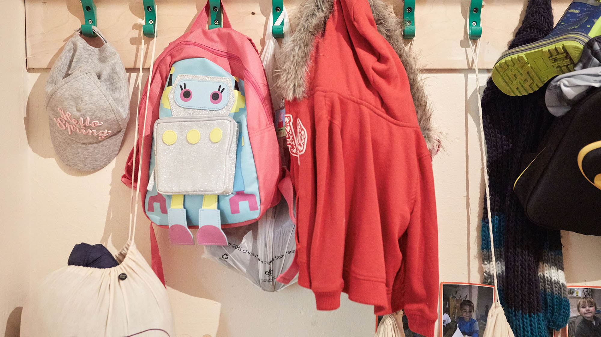 Children's backpacks and coats hanging up on coat rack