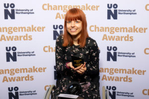 Kirstie Pope holding their Changemaker Student of the Year award