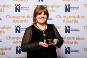 Karen Jones holding the award for Staff Changemaker of the Year on behalf of Paula Bowles