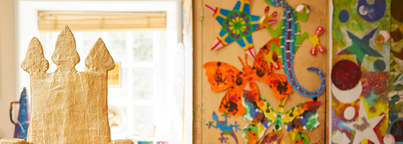 Colourful children's artwork hanging on the wall, including an orange and black butterfly and a blue and purple lizard.