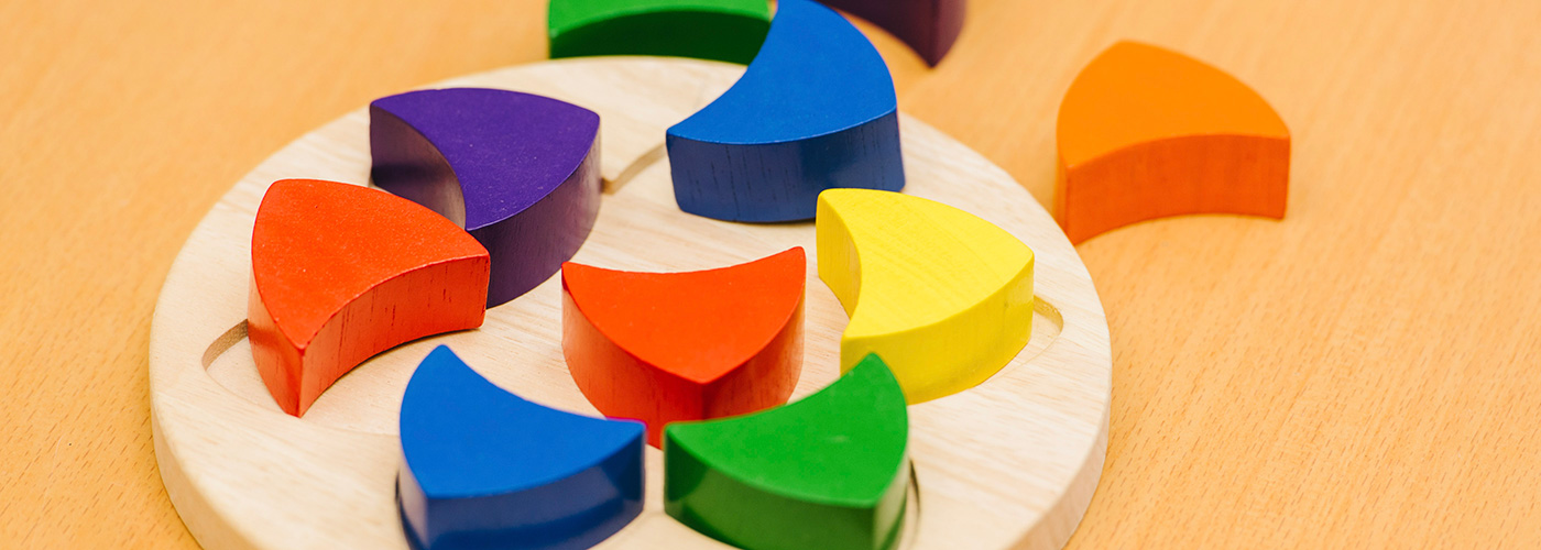 Colourful rounded triangle wooden shapes, in a wooden dish.