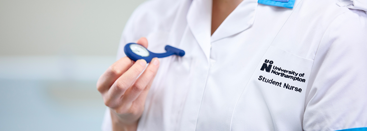 Student nurse holding watch attached to their uniform