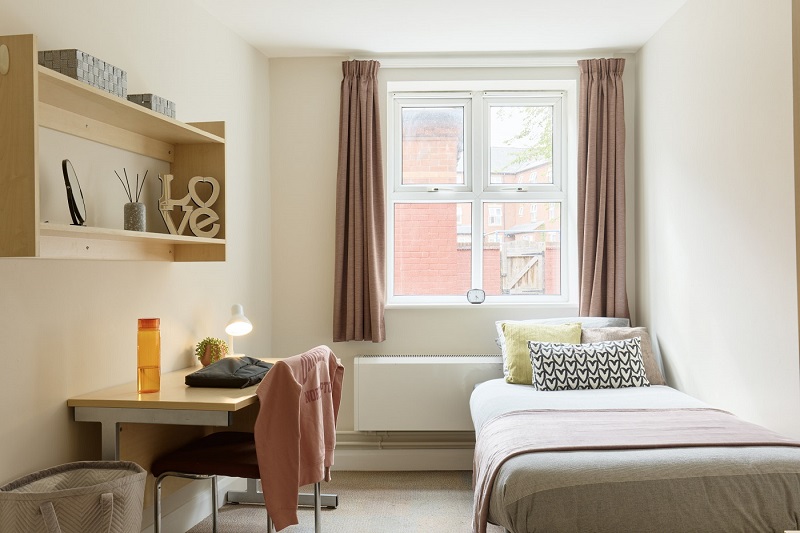 Desk, chair and bed in a standard single room in St Johns House