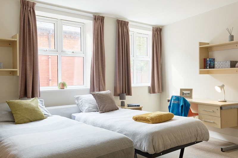 Two beds and a desk and chair in a twin room in St Johns House