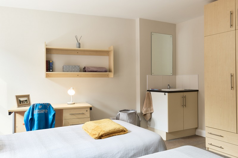 Bed, desk and sink in a twin room in St Johns House