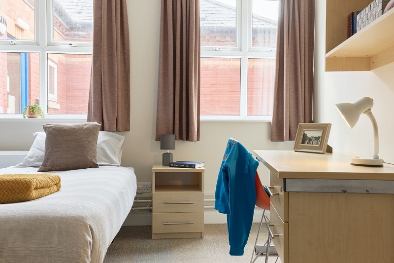 Bed and a desk and chair in a twin room in St Johns House
