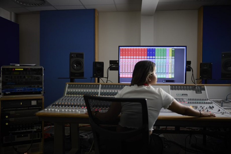 Student seated at a mixing desk in a UON music studio