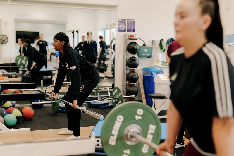 Two female students lifting barbells at the UON Sport Sciences gym.