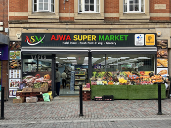 View of the front of the Ajwa Supermarket in Abington, northampton. There are stalls of fruit and veg and glass doors to the shop