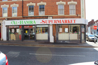 Outside view of the Al Hamra Supermarket on Kettering Road, Northampton. It is on the corner of a street. 