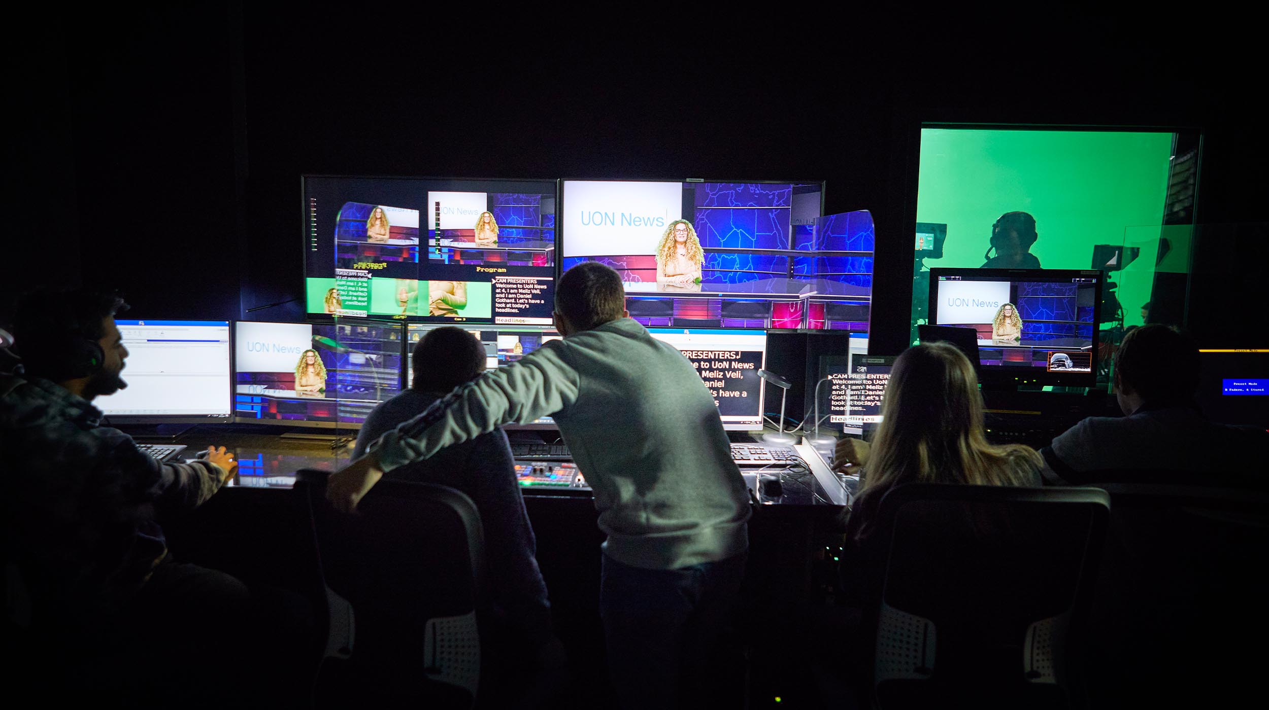 A group of Multimedia Journalism students work on multiple screens in the studio producing a news programme