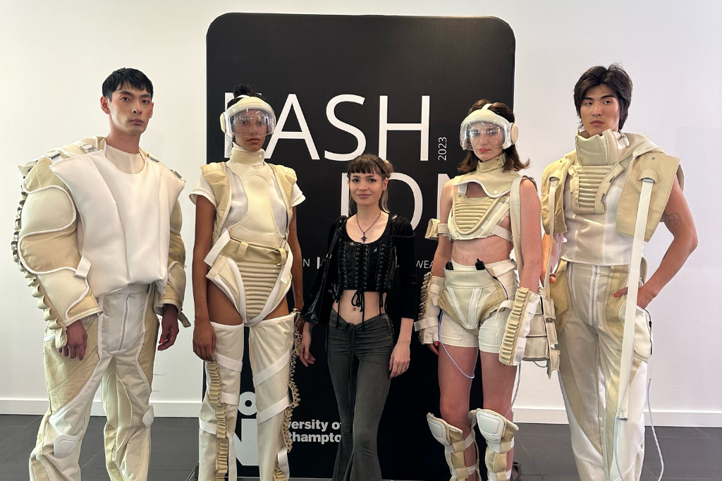 Amalia stands next to four models wearing clothing designs.