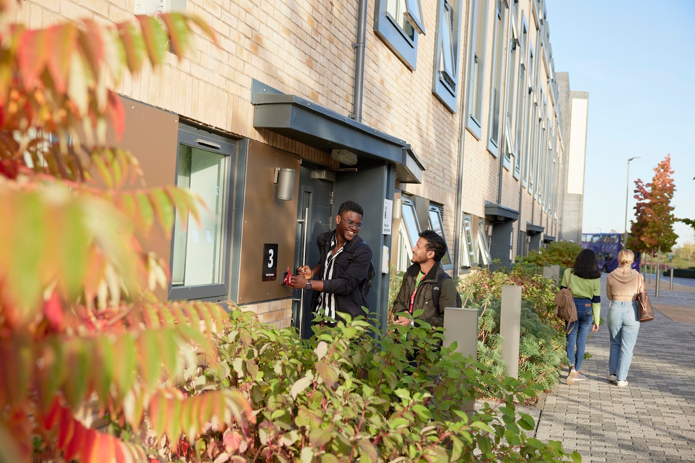 Two students are opening the front door of a town house at Waterside campus