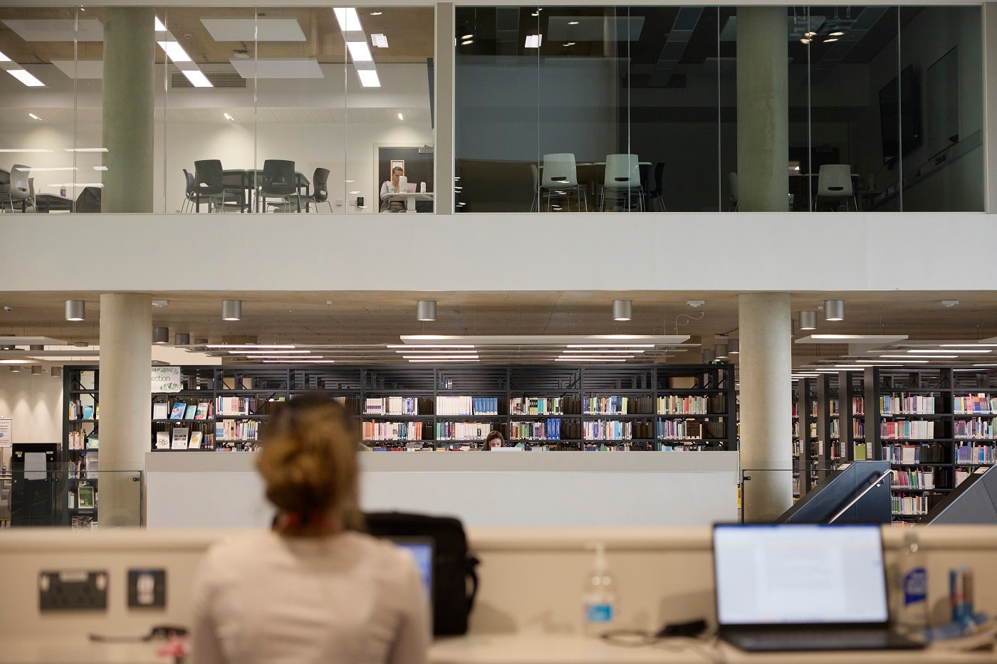 View of two floors across Learning hub atrium showing both library shelves and two glass-fronted classrooms