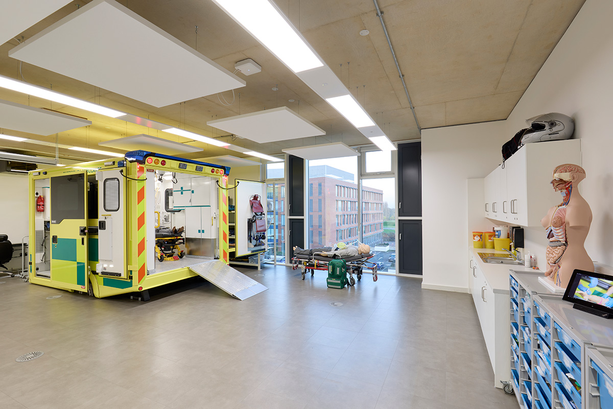 Internal view of the Paramedic Science suite, which has an ambulance simulator which is open and shows the inside and on the other side of the room is a mannikin with parts of the internal organ on display. There is also a kitchen area with cupboards.