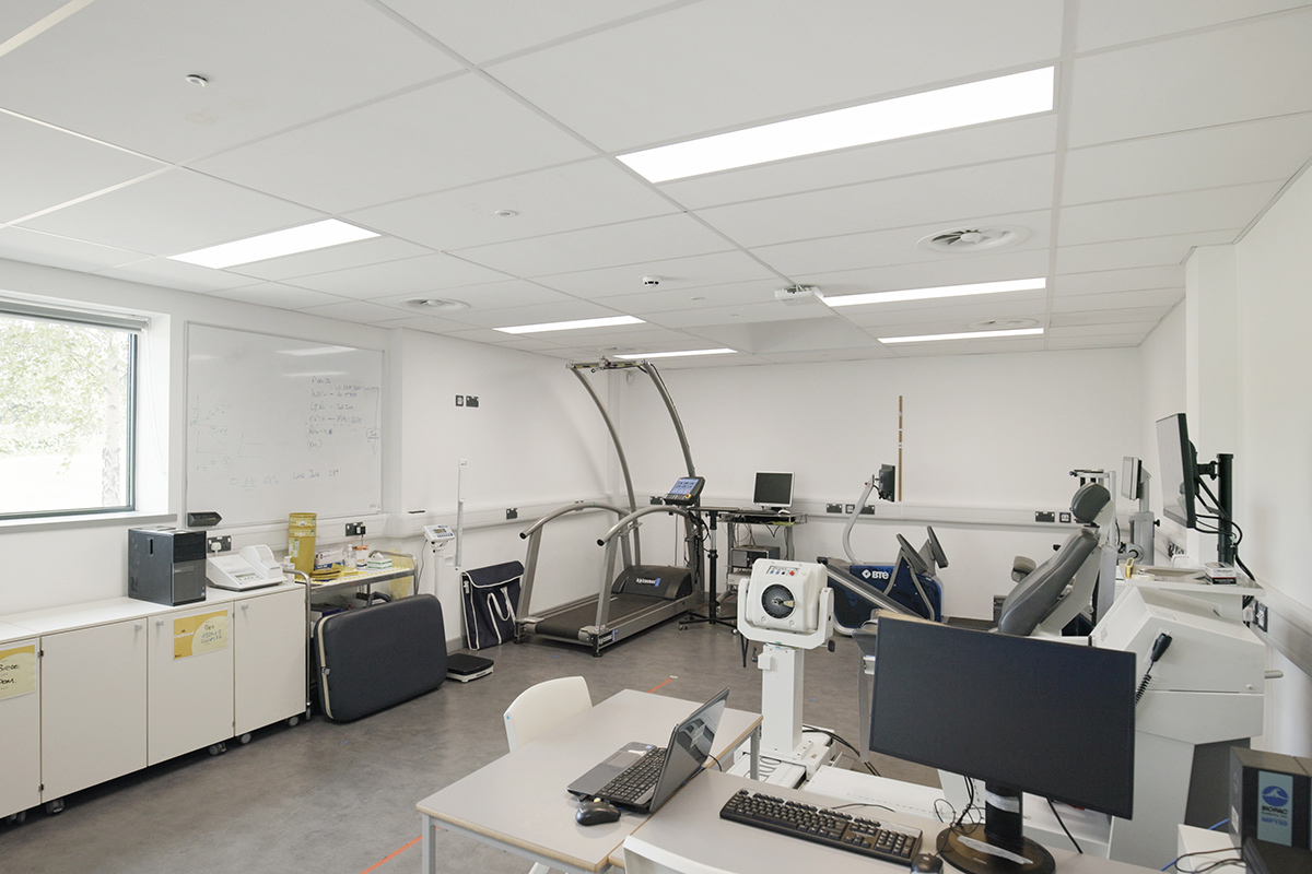 Internal view of the Sports Lab, which has a testing treadmill with handle grips and a computer next to it, along with other sports equipment plugged into computers and laptops. There are monitors next to all of the equipment, to be used to monitor those who use the equipment