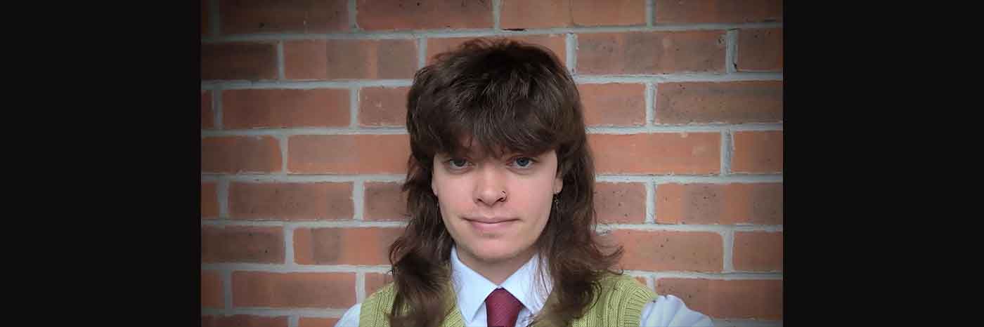 UON Geography BSc graduate Tyler Spencer Pote is pictured with a red brick wall in the background