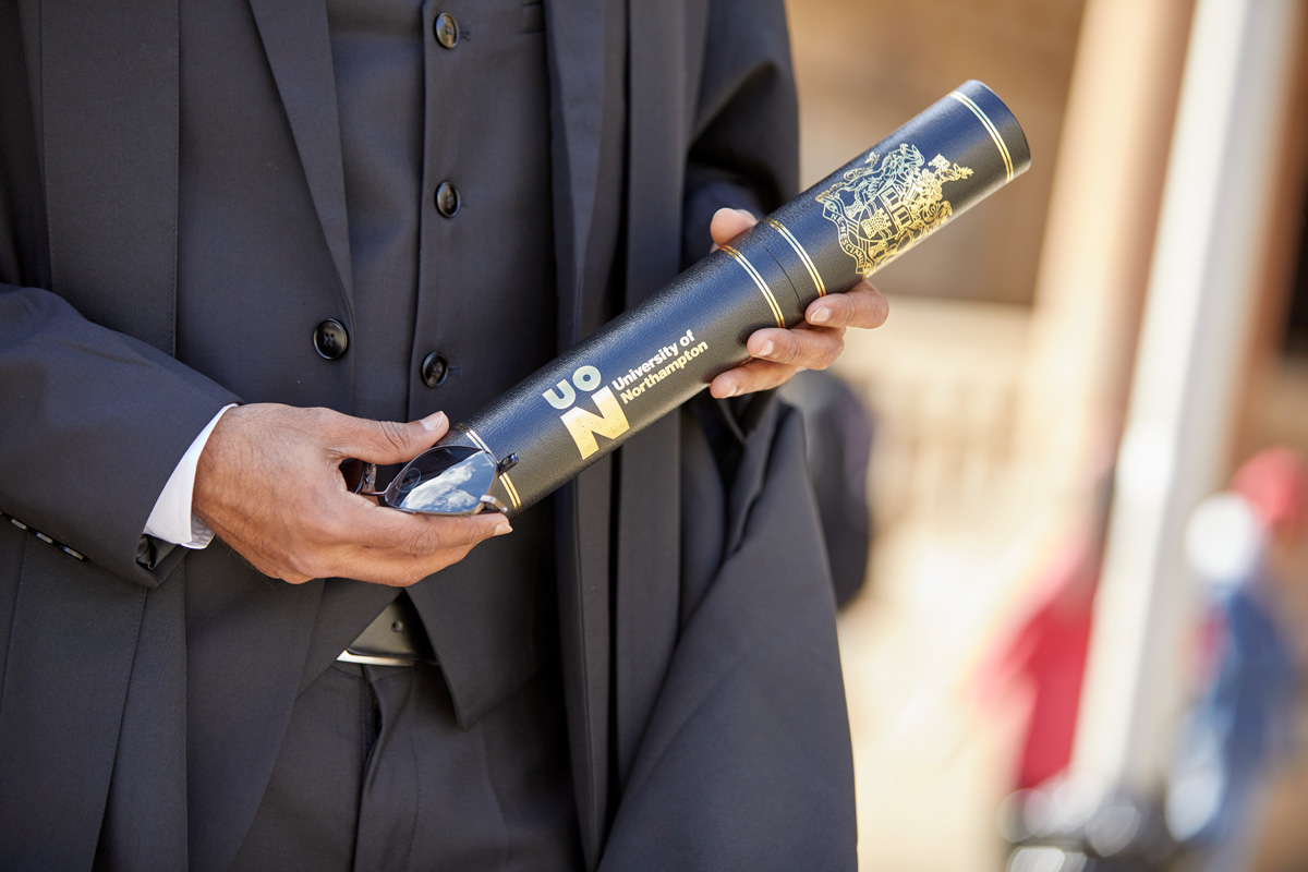 Pair of hands holding a UON scroll.
