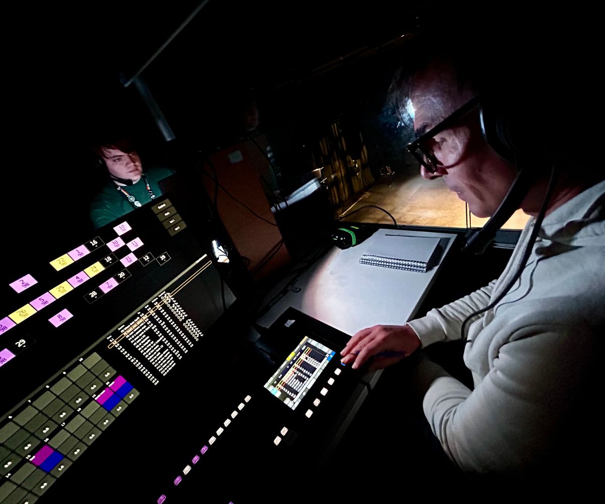 Live Production Technicians Alex Bass and Tim Halliday at a desk of digital screens and button used to control light and sound at UON's theatre space.