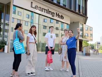 Student ambassador taking 4 guest on a tour in front of the Learning Hub.