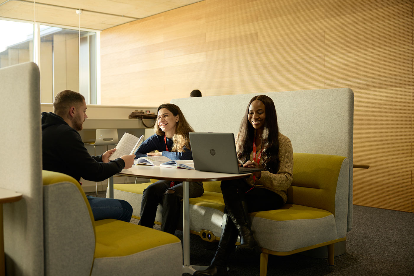 Three students sit at a booth in the library