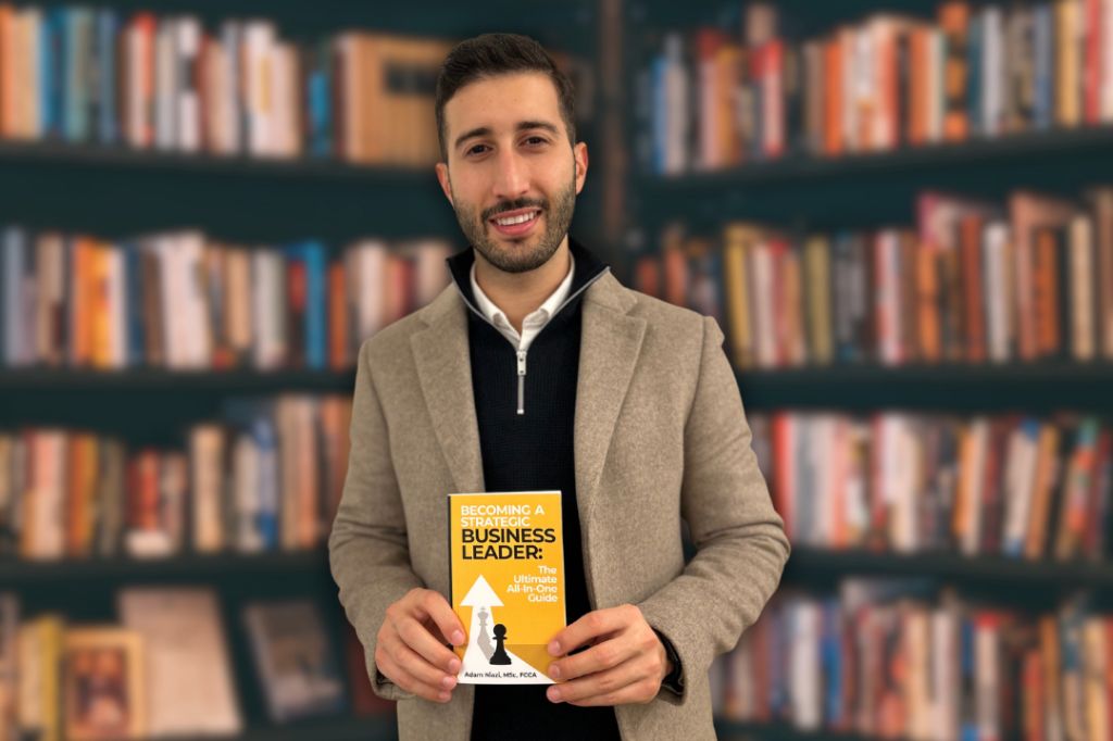 Adam Niazi stands with is book Becoming a Strategic Business Leader: The Ultimate All- In-One-Guide.