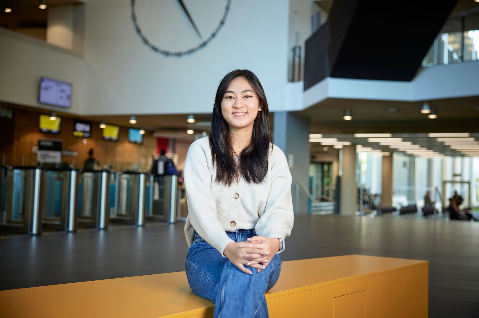 Student sat with the Learning Hub clock behind her.