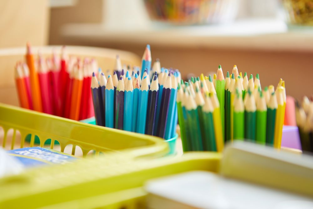 Colorful pencils in a basket on a desk.