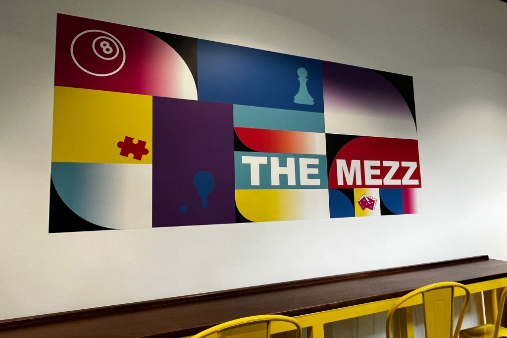 The Mezz branding on the wall in front of bar stools.