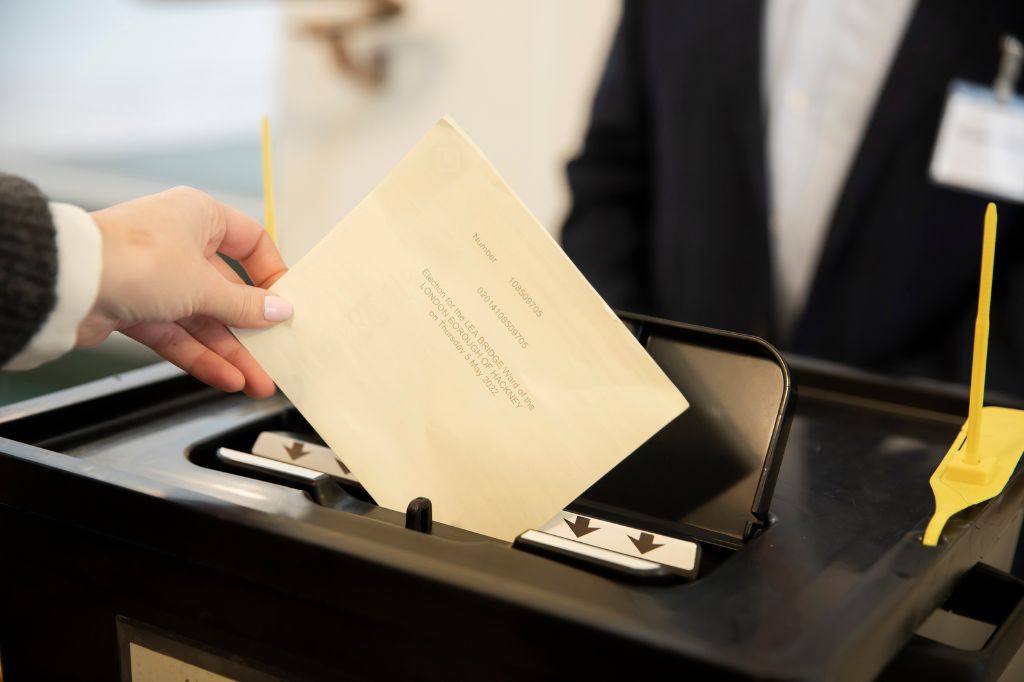 Voter placing ballot card in to a ballot box.