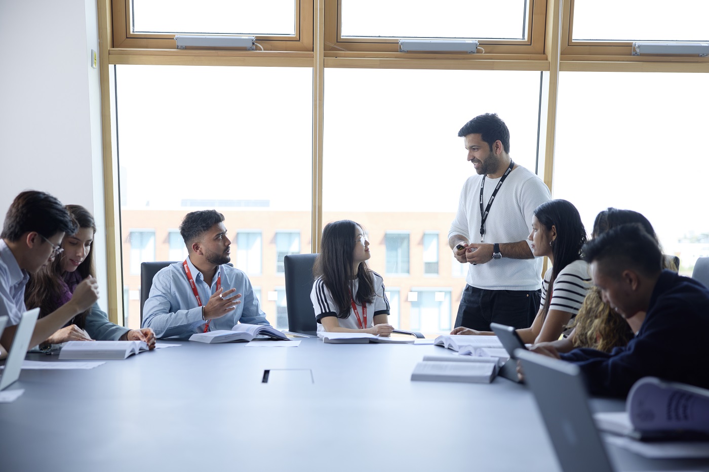 An academic discusses a topic with students seated at a conference table in an MBA class.