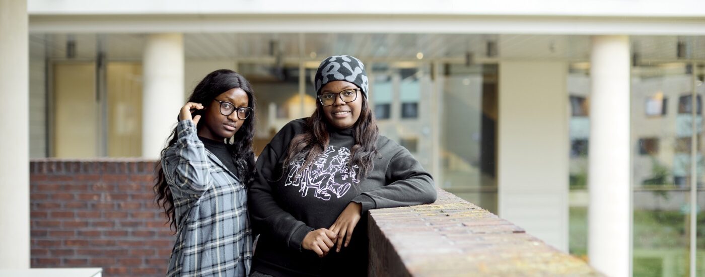 Two students stand on a brick-edged balcony in the Learning Hub.