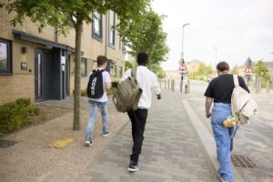 Three students with rucksacks on their backs walking down Park Avenue at Waterside campus.