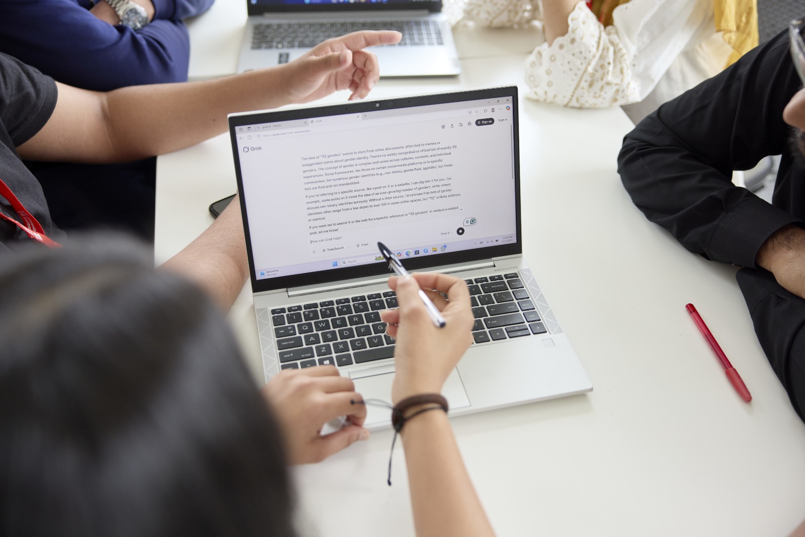 An image of a UON free HP laptop issued to a student with a word document on it and a students hand pointing a pen towards it.