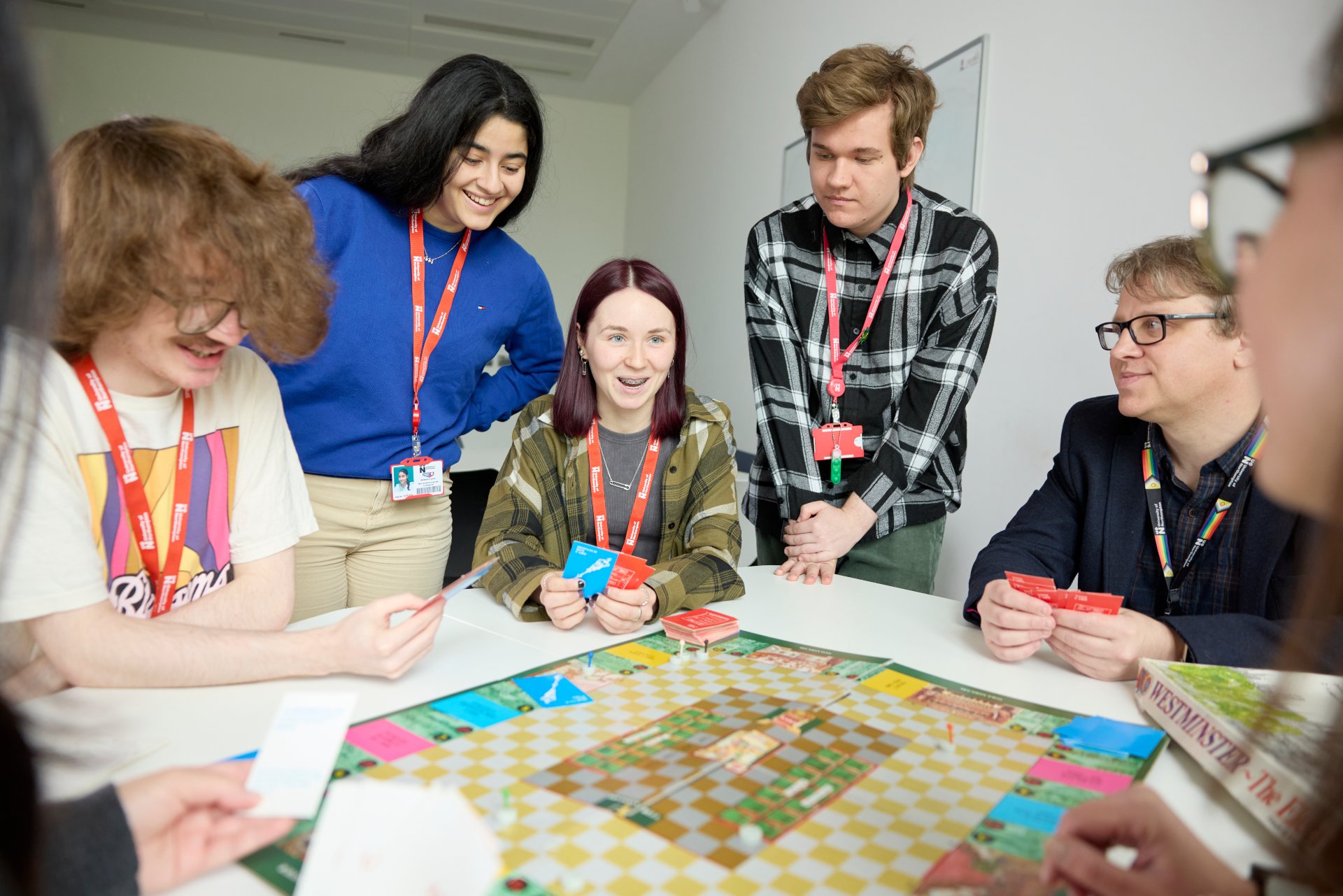 Students gathered around a table playing a colorful board game, actively engaged in a group activity during a workshop