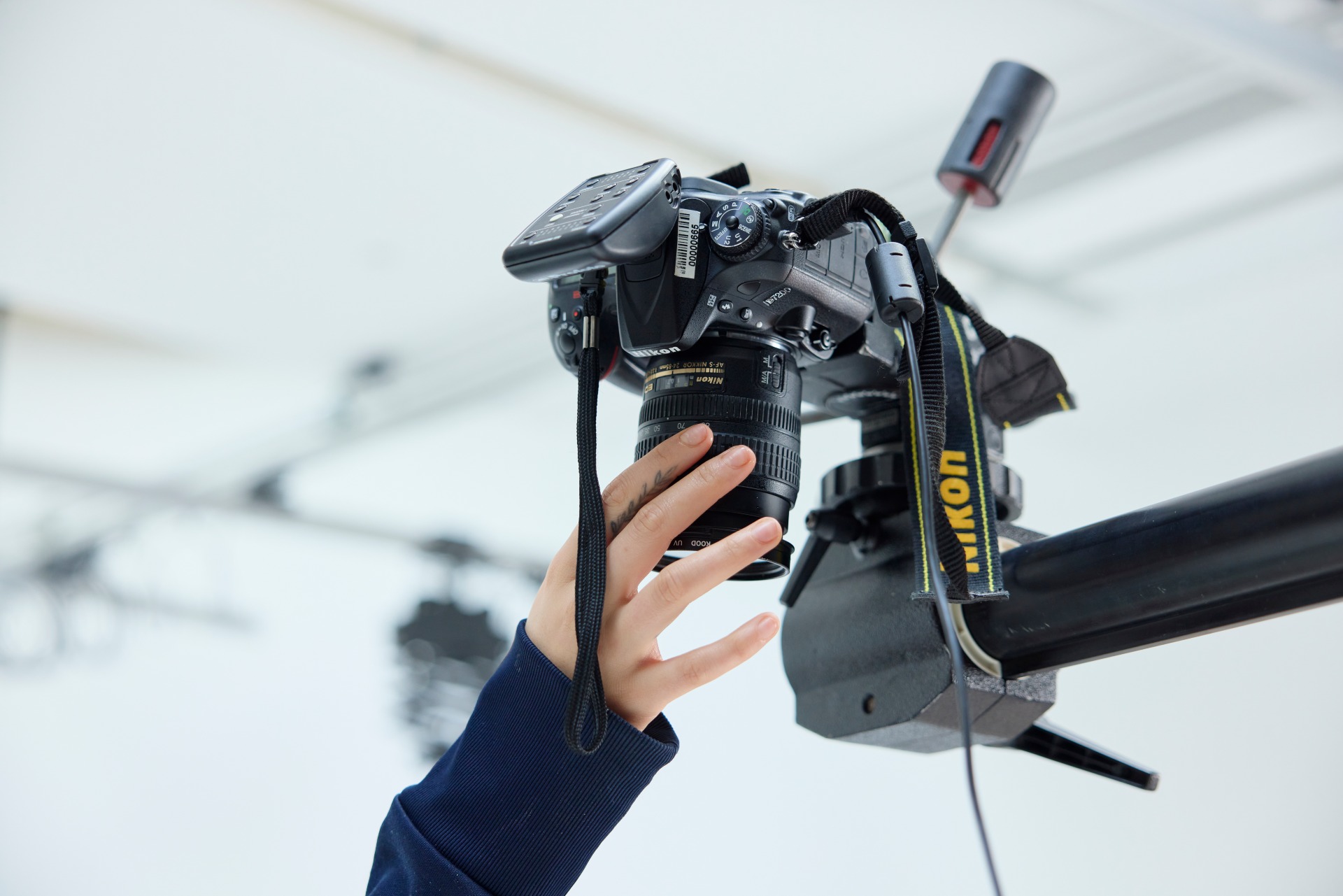 Close-up of a student adjusting a DSLR camera mounted on an overhead rig during a photography studio workshop