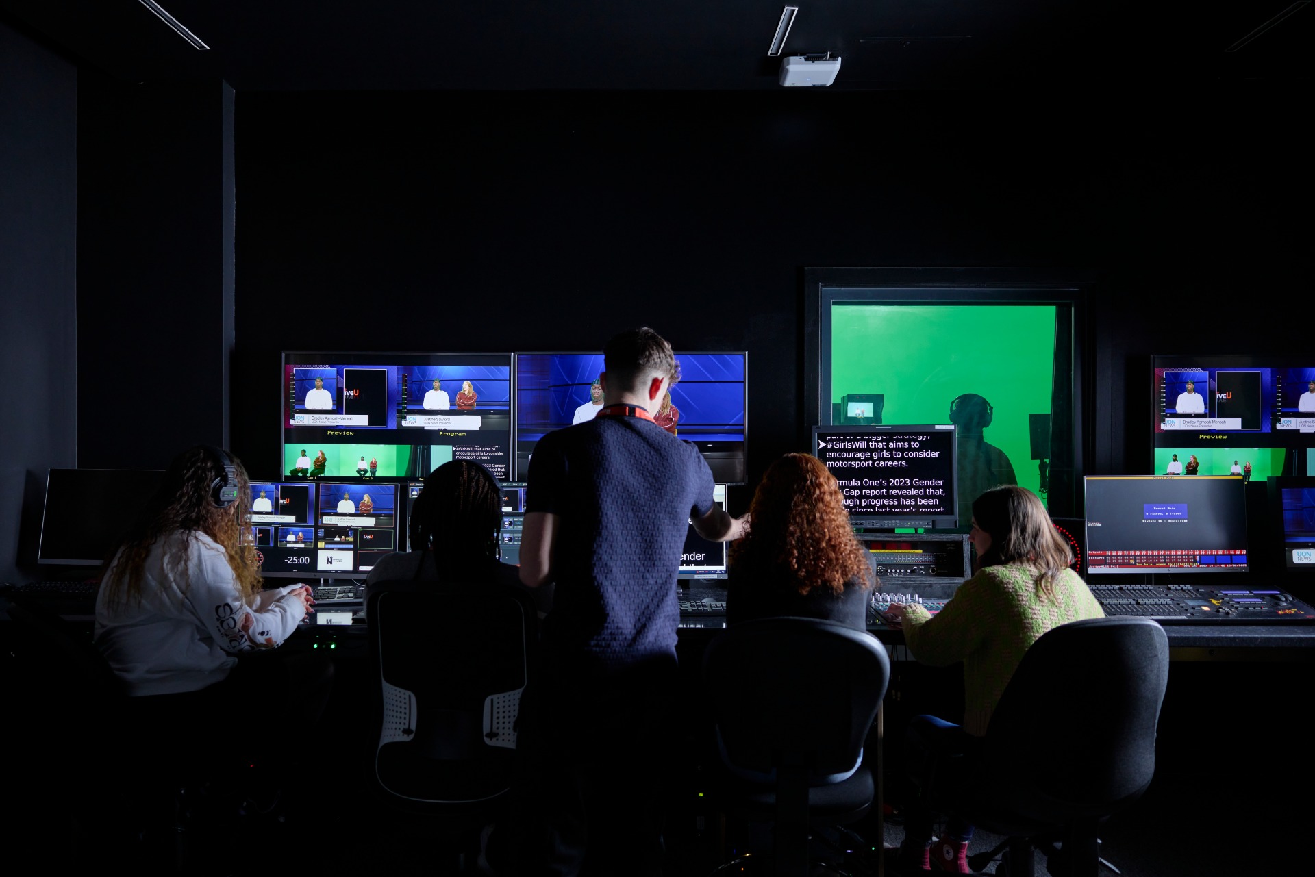 TV studio control room with students managing live production, monitoring multiple screens showing presenters in front of a green screen