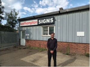 Ishmam stood in all black outside the Northampton Signs company building.