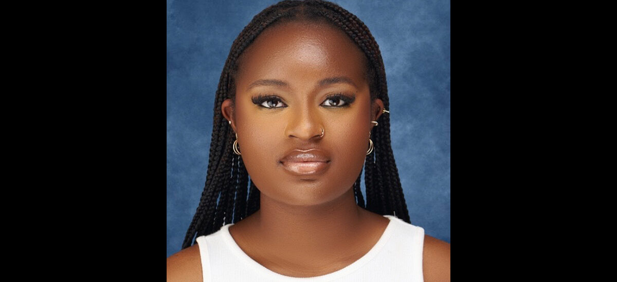 Stephanie Oko, BA (Hons) Business Management graduate wears a white sleeveless top in front of a blue textured background.
