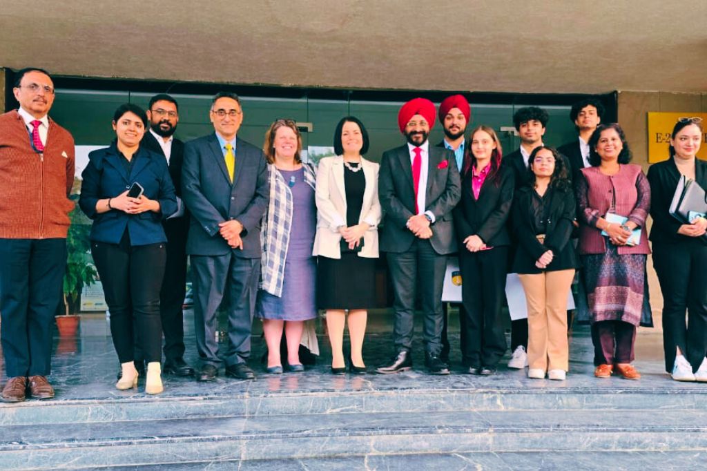 A group of people dressed in formal and semi-formal attire stand together outside a building, posing for a group photo.