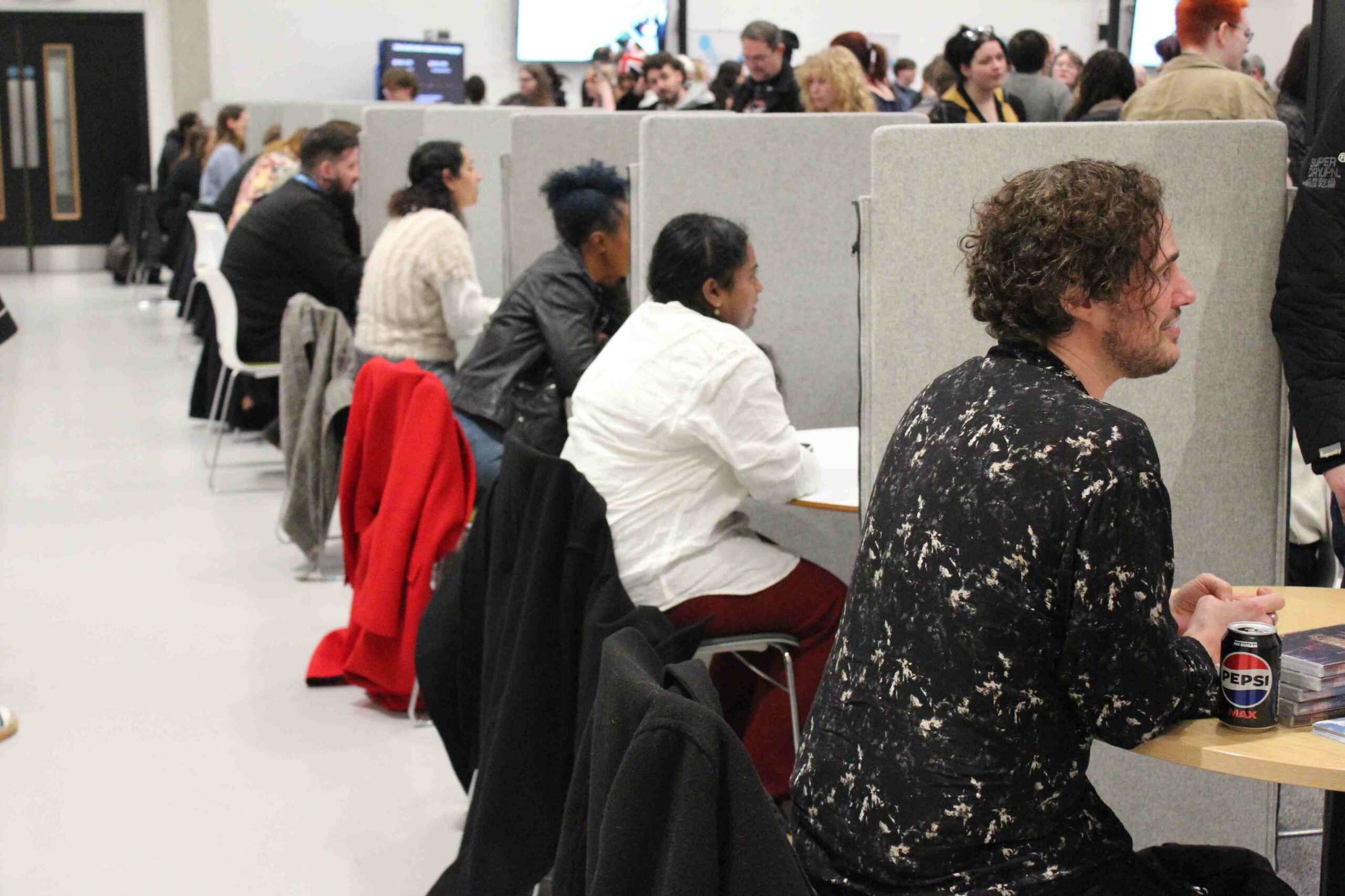 Ten people face a crowd of people seated in chairs in conversation.