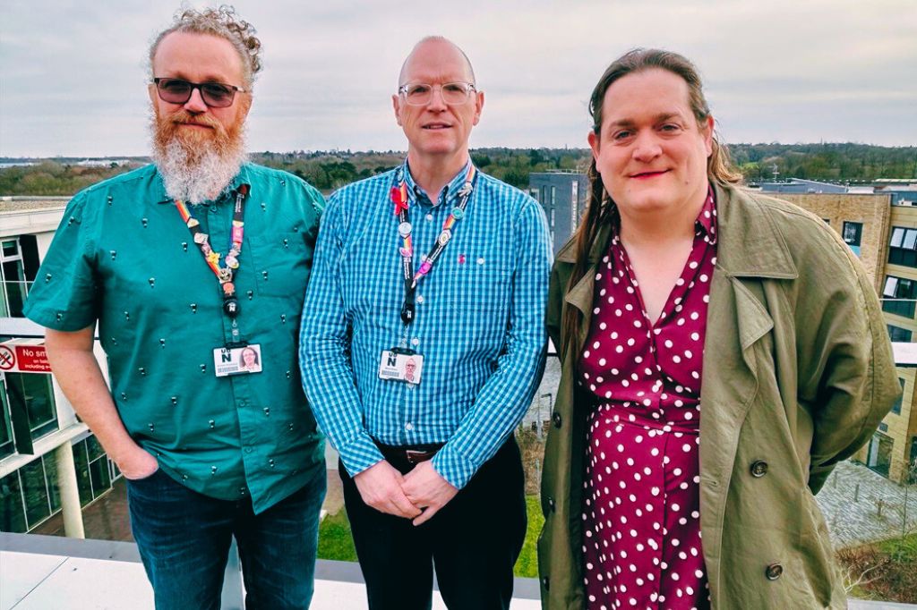 Professor Simon Sneddon, Nick Allen and Rebecca Steers stand shoulder to shoulder on a balcony at the Waterside Campus overlooking the treescape to the south.