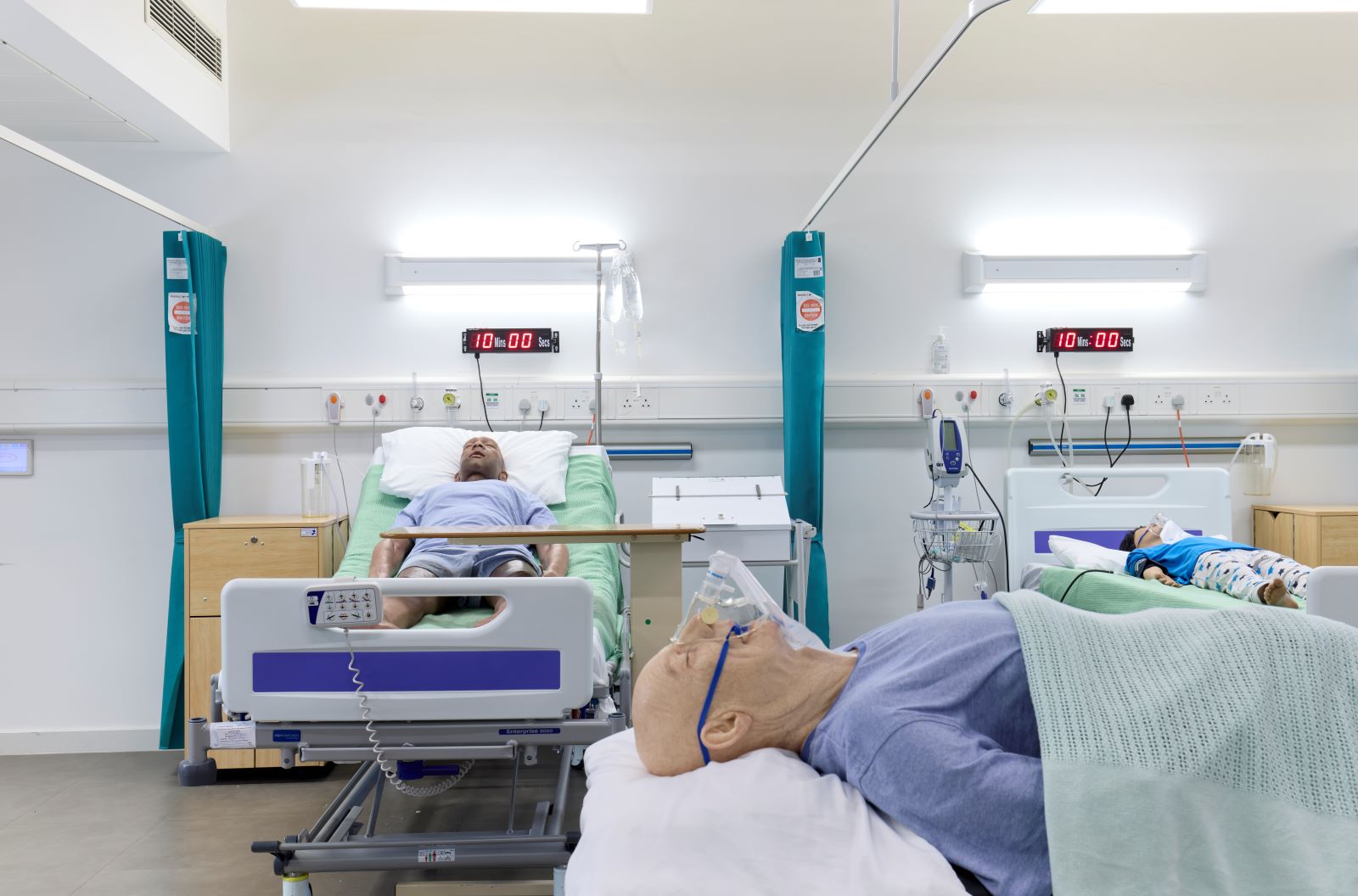 View of three medical mannequins on beds in the Nursing suite. The mannequins represent different ages including a child and an elderly man.