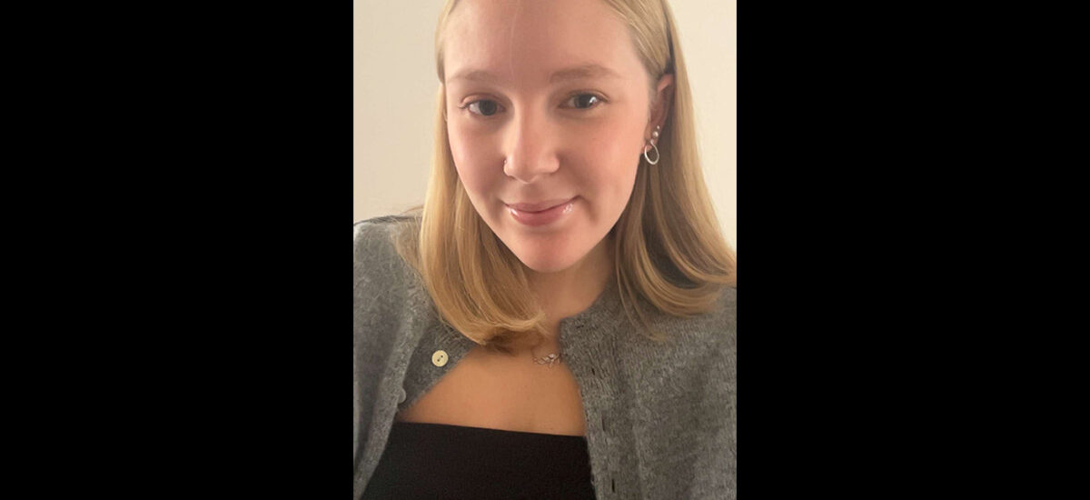 Grace Hunkin, UON Business Management BA student. She is wearing a black top with a light grey cardigan and is smiling at the camera.