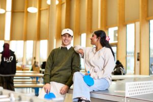 Image of two students leaning against a table tennis table in the Market.