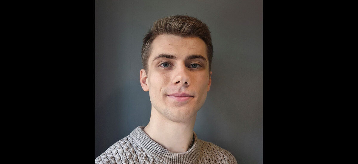 Harrison Copp, Geography BSc student. He is wearing a light brown sweater and is smiling at the camera.